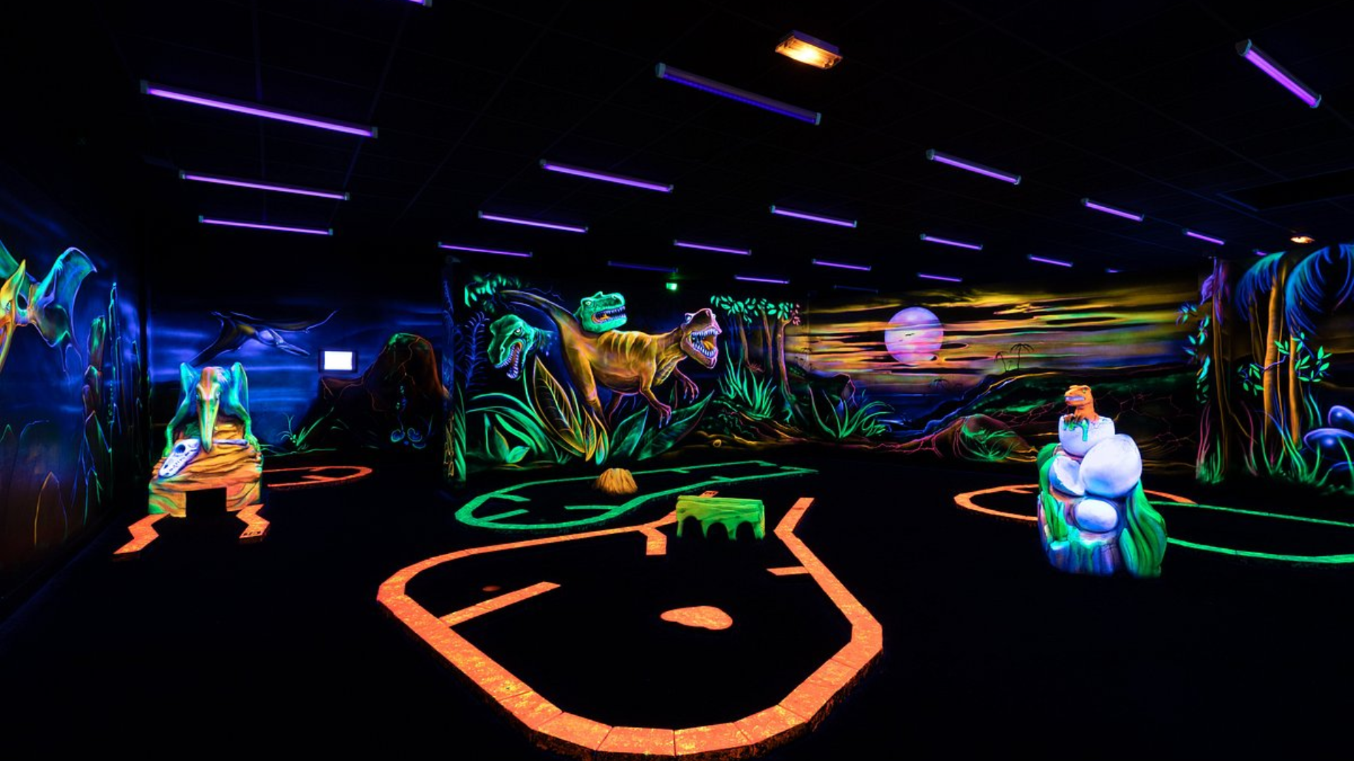 Fresque de dinosaures peinte en fluo le long du parcours de mini-golf indoor de Montauban