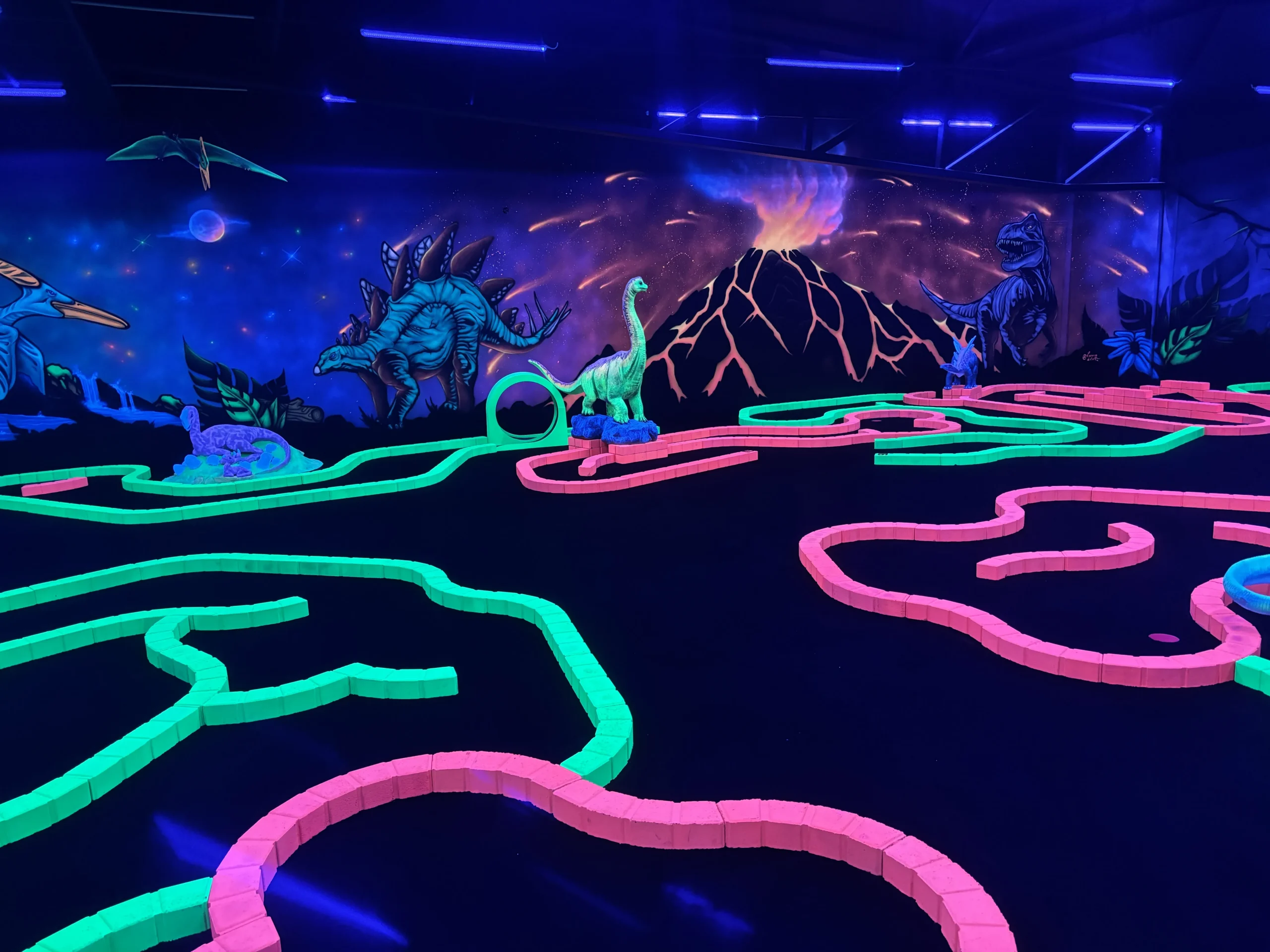 Vue d’ensemble des pistes fluo et du décor préhistorique du mini golf de Montauban