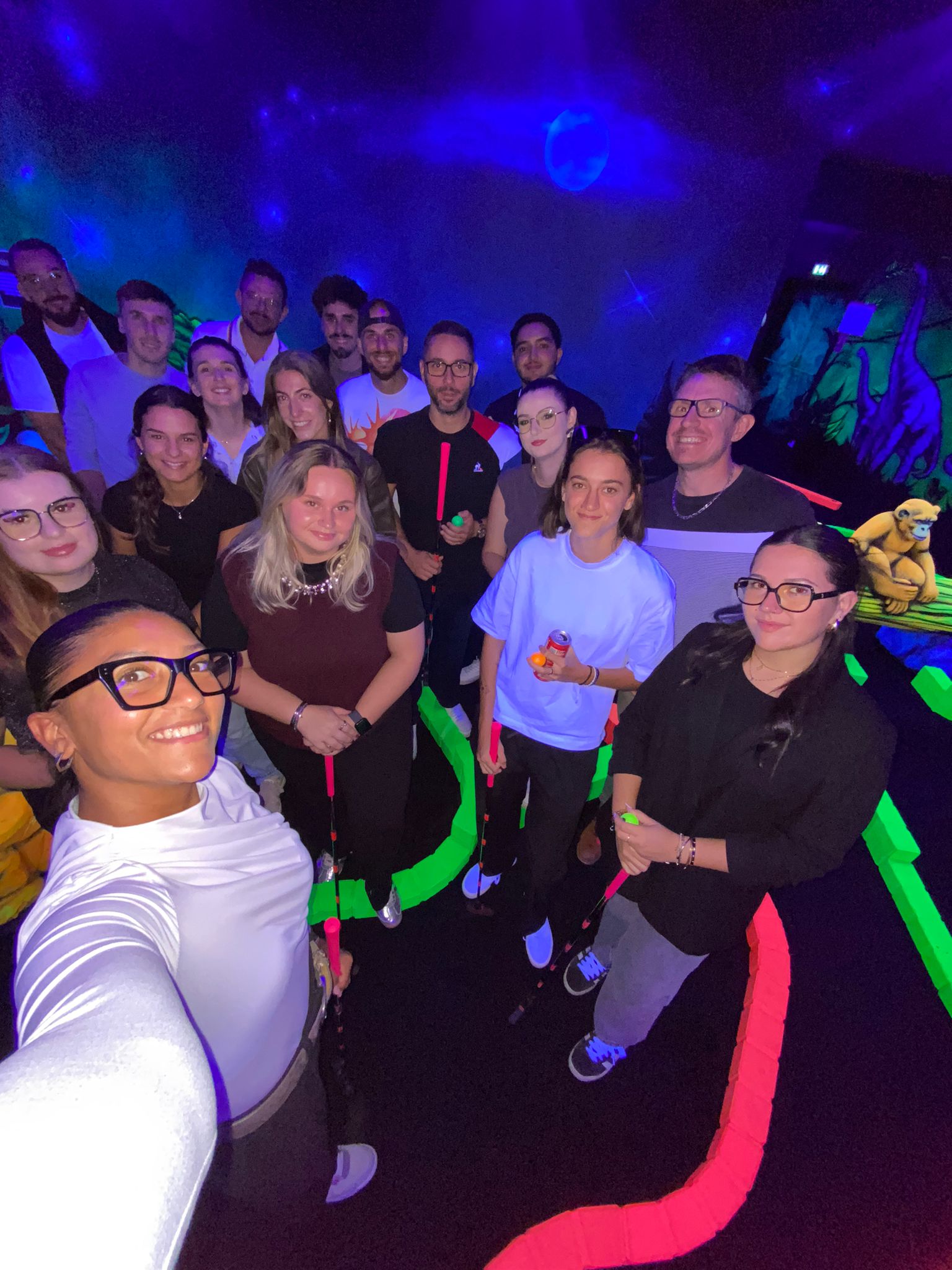 Groupe de joueurs réunis dans la salle du mini-golf fluo de l’Arena Montauban