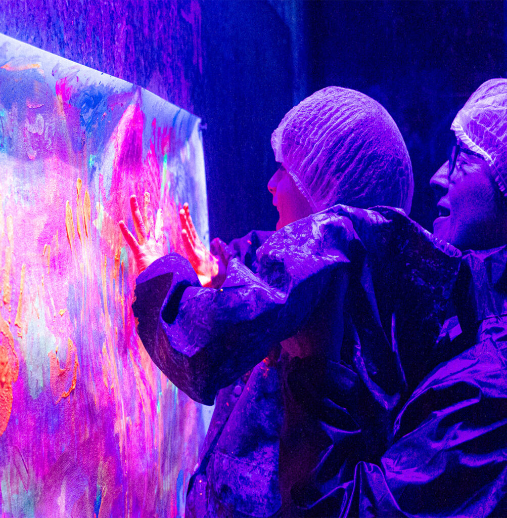Mains couvertes de peinture fluorescente sur le mur de la Color Room Montauban
